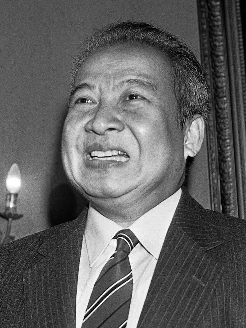 Black-and-white portrait of a smiling older man in a pinstriped suit and striped tie