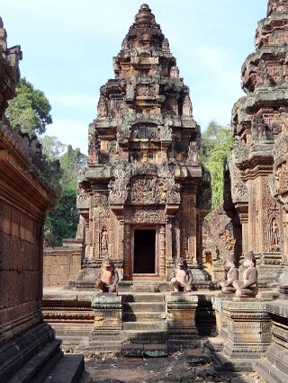 A narrow, finely carved pink sandstone tower with a doorway at its base.