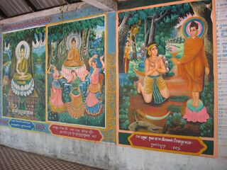 A row of brightly painted panels showing scenes from the life of the Buddha, with captions below.
