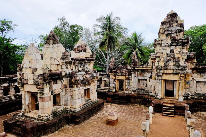 Weathered stone sanctuary towers on a low platform, with palm trees behind.