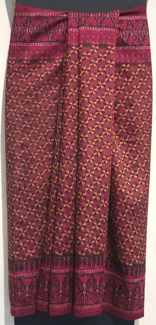 A long red silk skirt cloth with a fine diamond pattern and a deep patterned border at the hem.