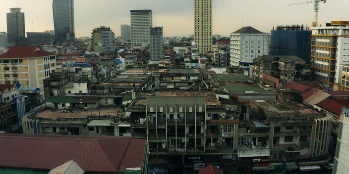 Rooftops of low and mid-rise buildings with a few towers and a construction crane on the skyline.