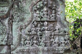 A weathered sandstone panel carved with rows of small seated figures around a central figure.