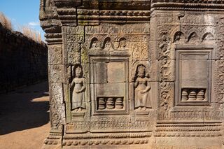 A sandstone wall section carved with two standing female figures beside a decorated panel.