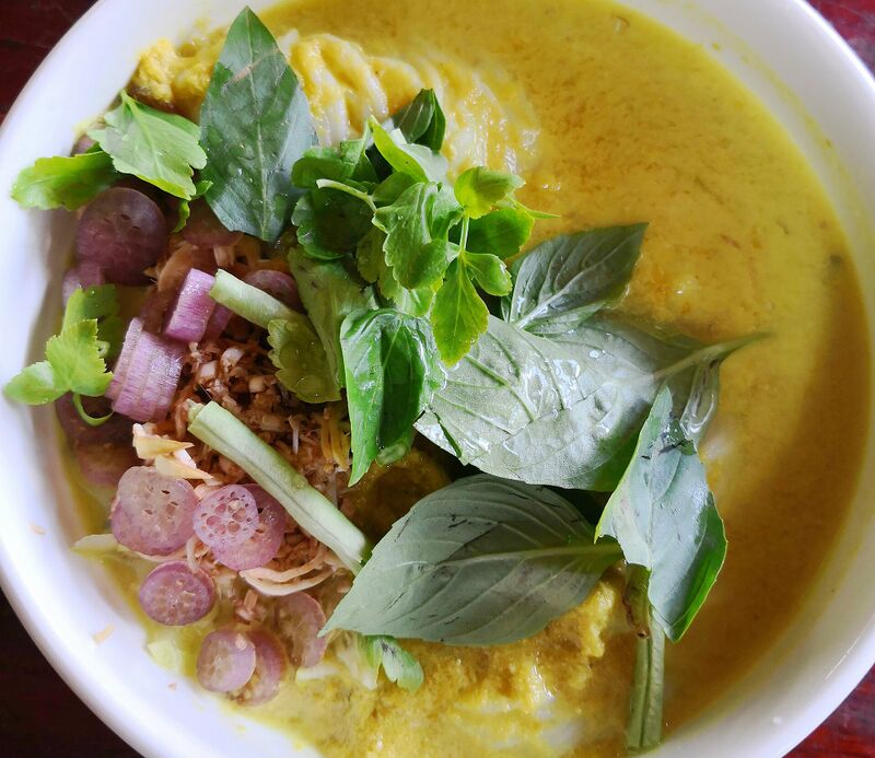 Rice noodles in a yellow-green fish broth topped with basil, cucumber, banana flower and shallot.