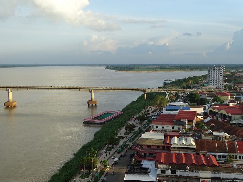 A wide river with a long bridge across it, and the town's red roofs along the bank in the foreground.