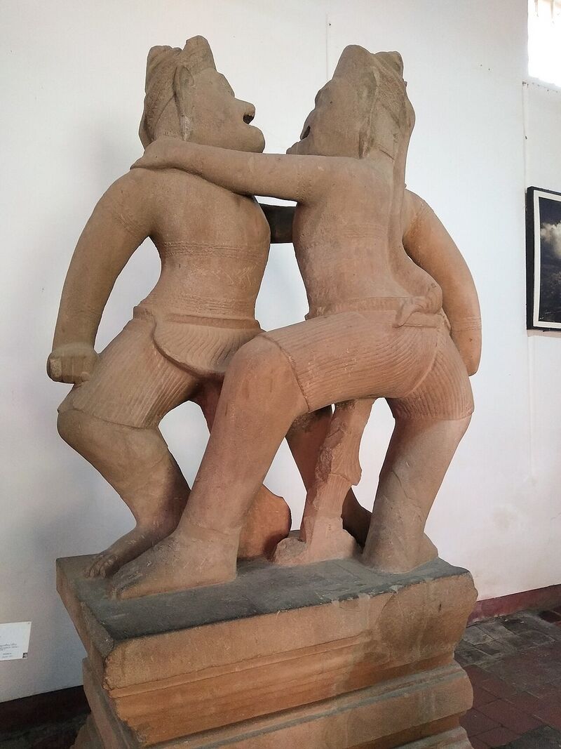 Two carved apes locked in a wrestling hold on a stone base, shown in a museum display
