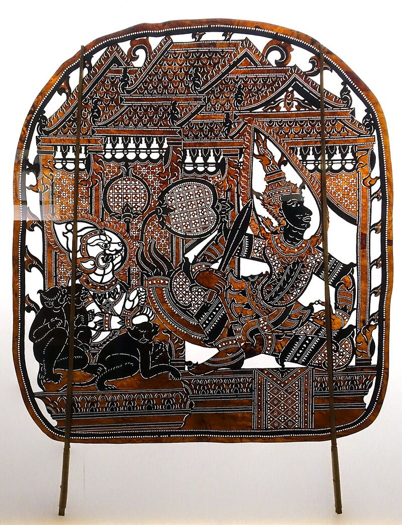 A dark leather panel cut with lacy patterns showing figures, mounted on two sticks.
