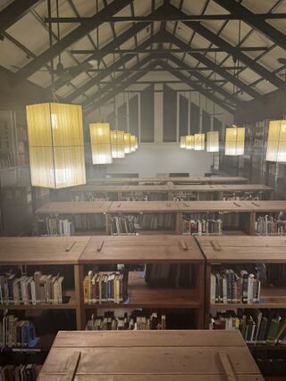 Rows of low wooden bookshelves under a high timber roof hung with large paper lanterns.
