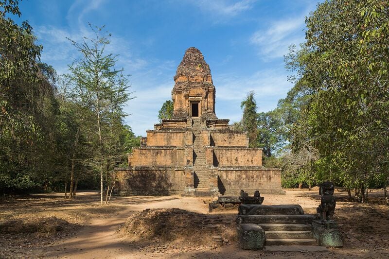 A small brick tower on a four-tiered stepped pyramid base in a clearing among trees