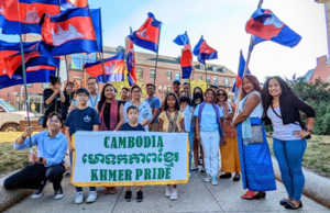 A group holding Cambodian flags and a banner reading Cambodia Khmer Pride on a city sidewalk.