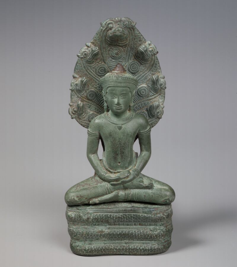 A green-patinated bronze Buddha seated in meditation on the coils of a serpent whose seven hooded heads rise behind him.